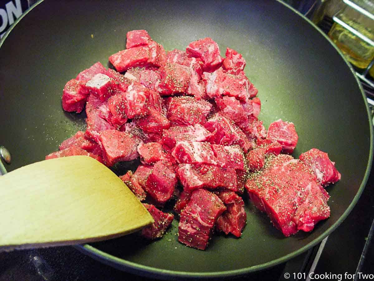 seasoned chunks of beef in a skillet.