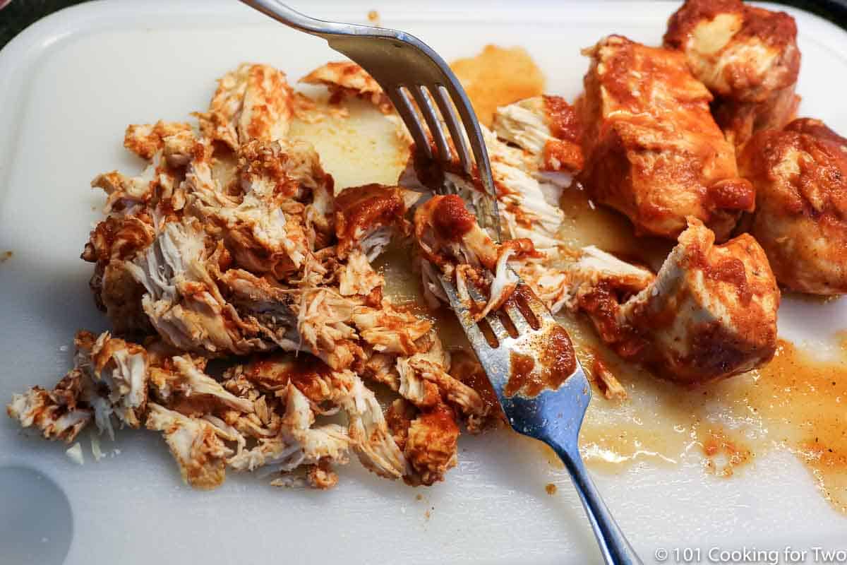 shredding chicken on a white board.