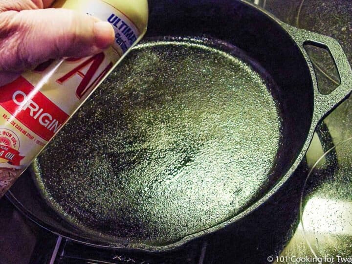 spraying a cast iron skillet with PAM