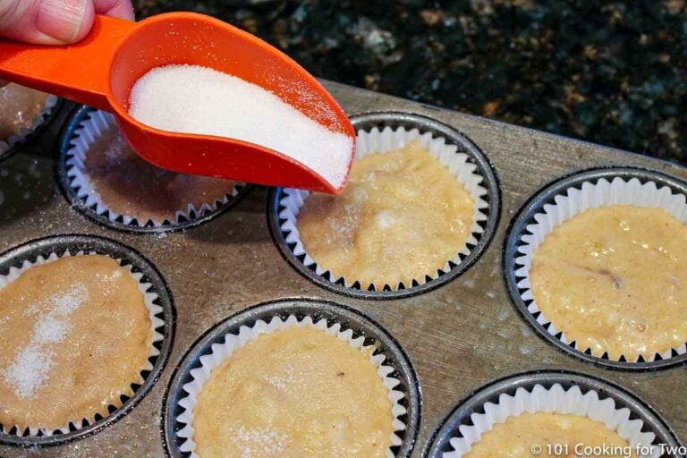 sprinkling sugar on top of uncooked muffins