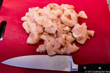 trimmed chicken with knife on a red board