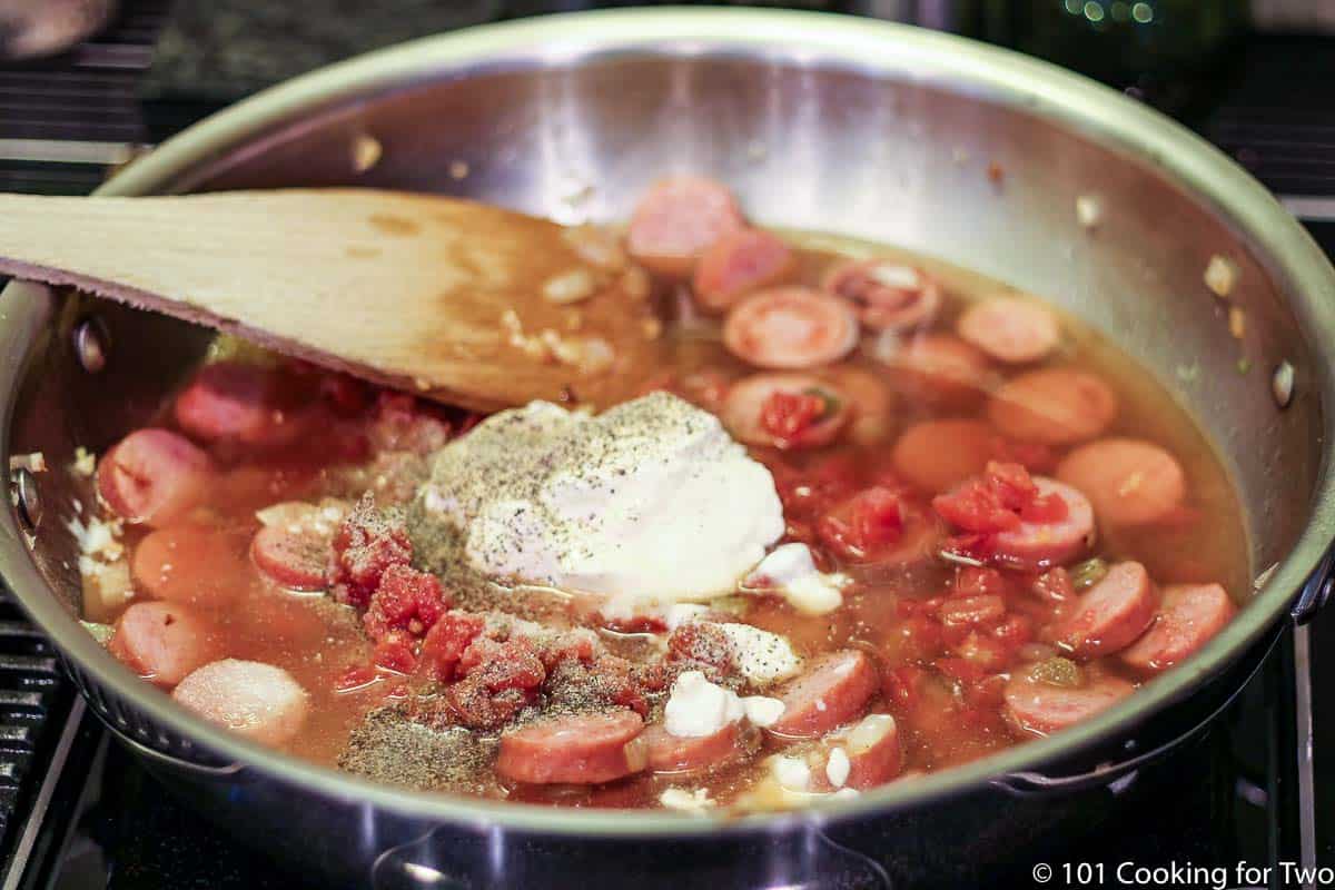 adding sour crean and broth to cooked sausage.