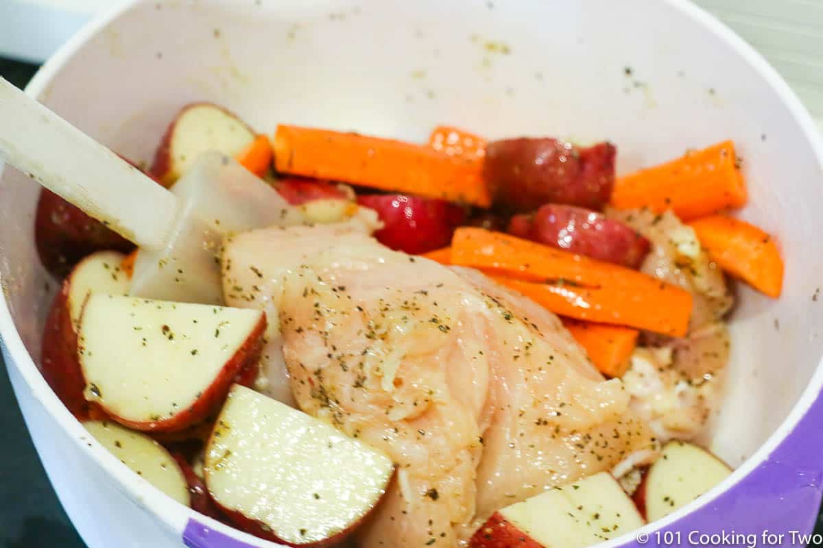 coating chicken and vegetables with oil and seasoning