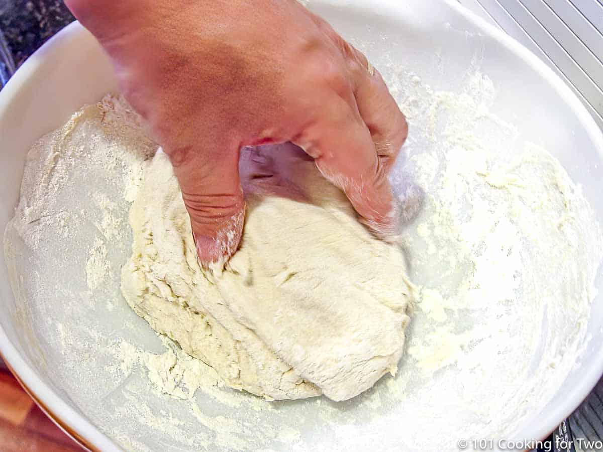 hand kneeding dough in a large bowl