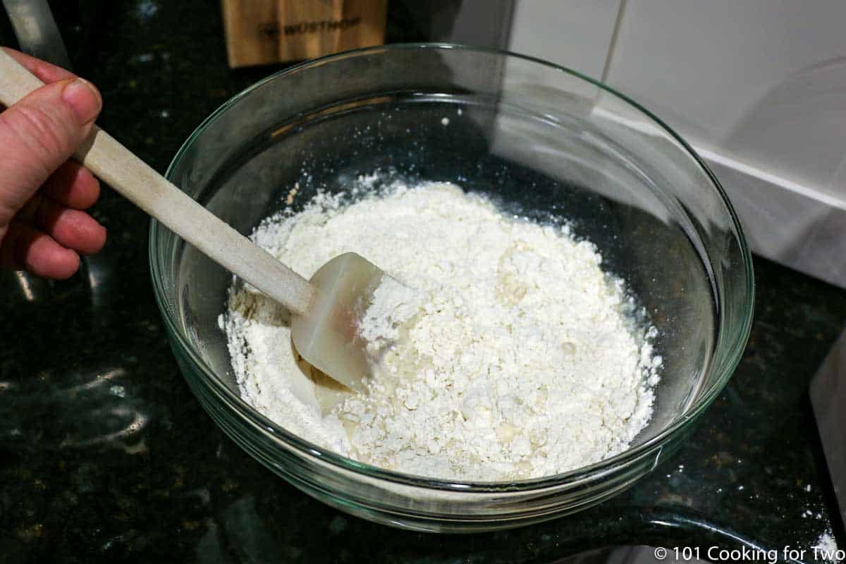 mixing flour into wet ingredients in a glass bowl.