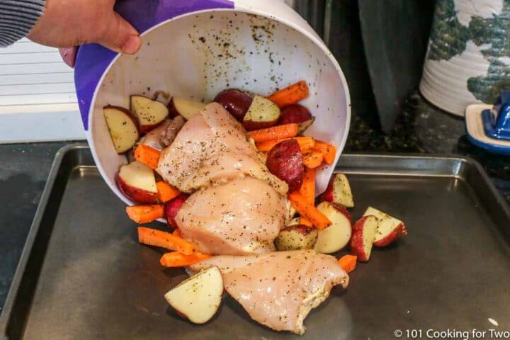 pouring chicken and vegetables onto baking tray