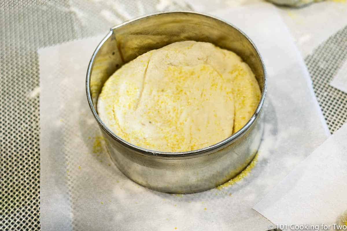 raw dough in baking ring on a piece of parchment paper.