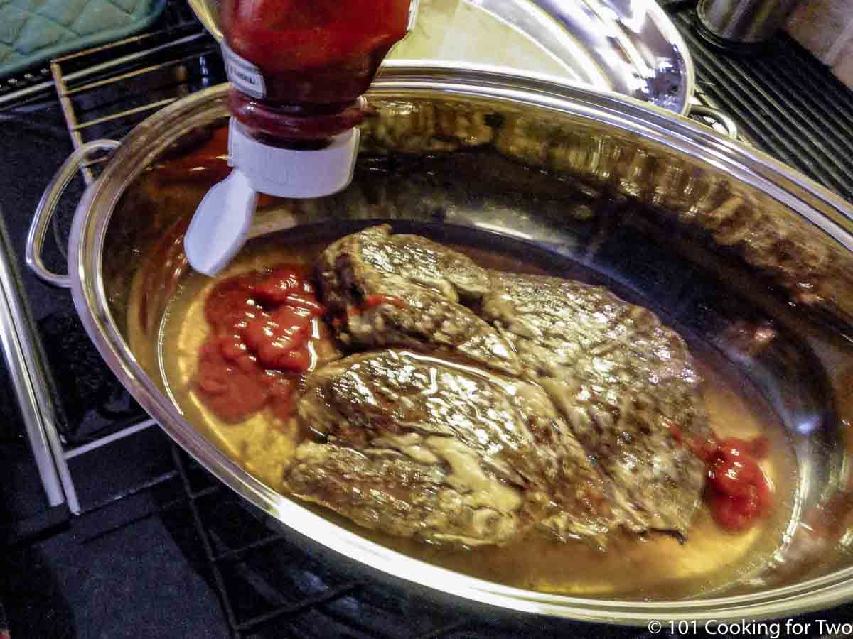 adding ketchup to roaster with cooked crock pot.