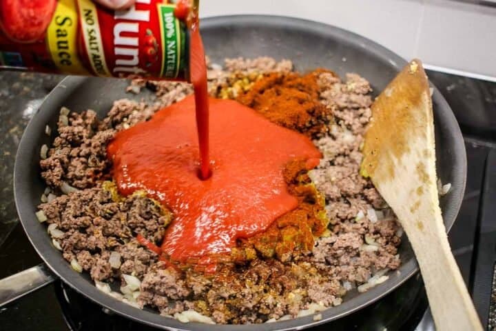 adding tomato sauce to browned burger