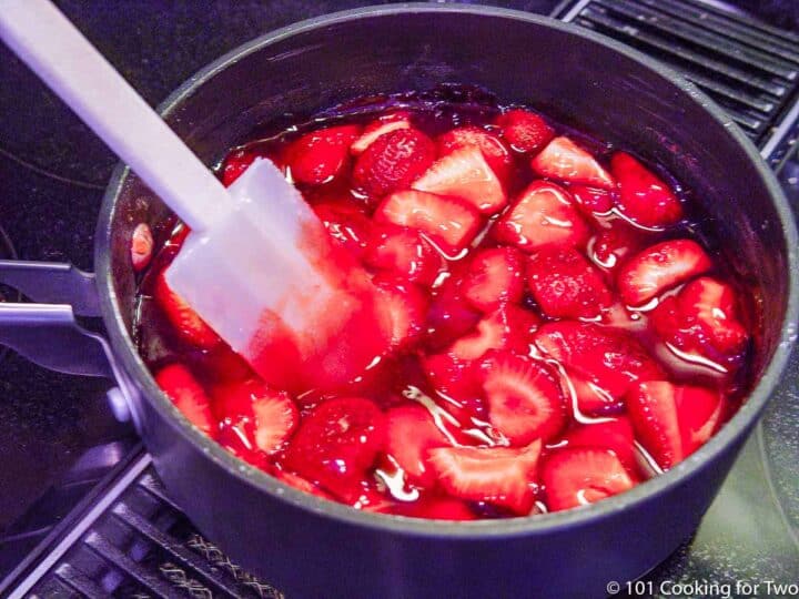 mixing fresh strawberries into sauce