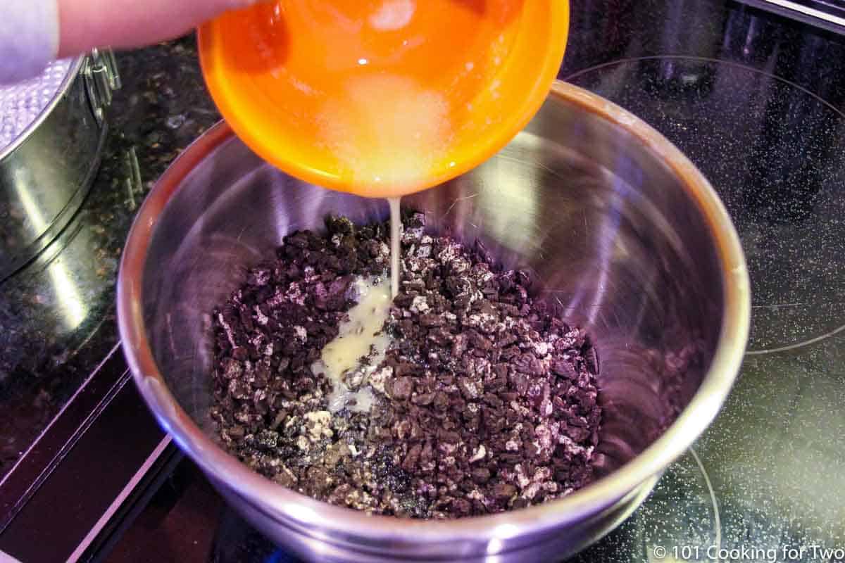 pouring melted butter into chopped Oreos