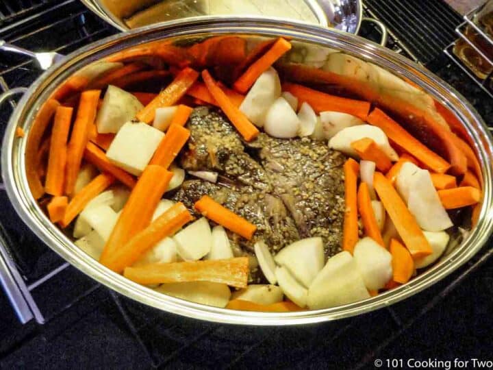 raw potatoes and carrots spread over the cooked roast
