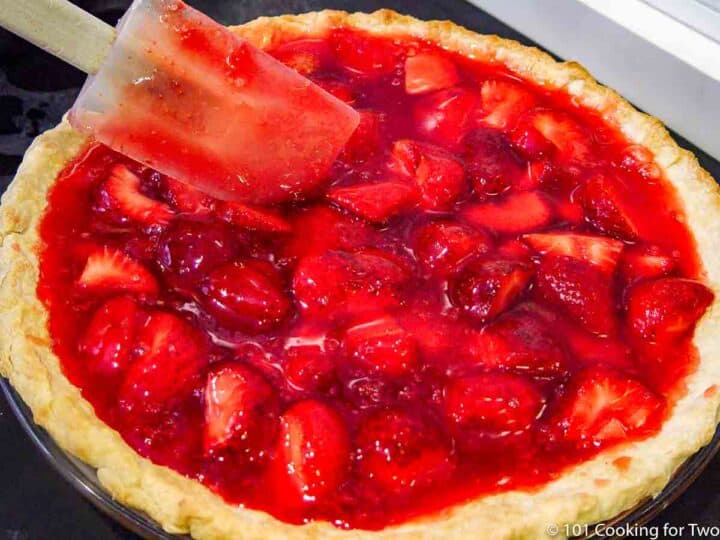 smoothing top of strawberry pie after filling crust