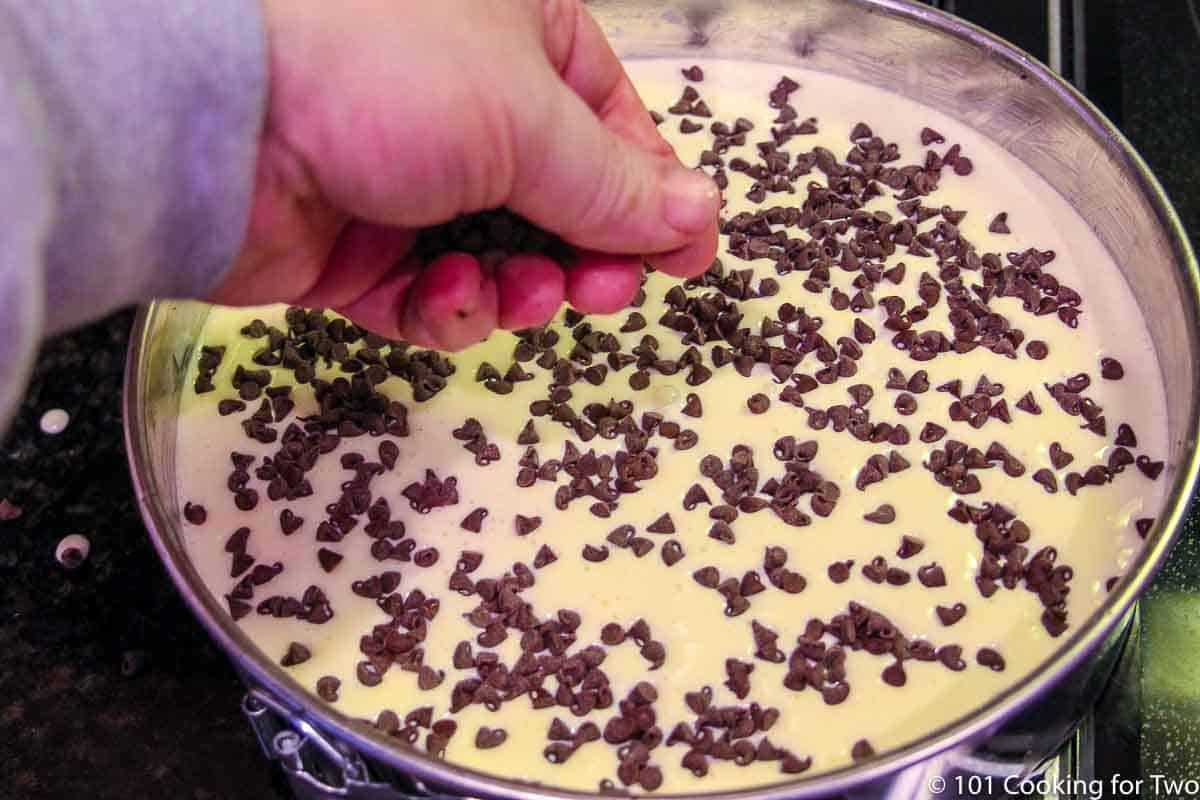 spreading chocolate chips over cheesecake