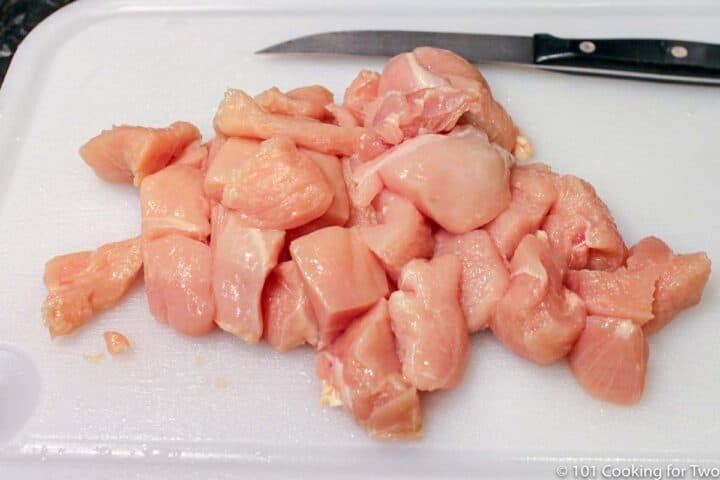 trimmed and cubed raw chicken on white board