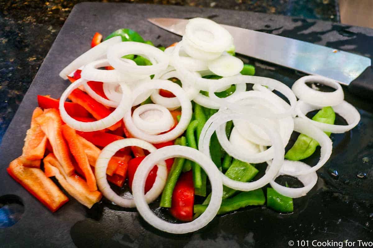 Trimmed onion and peppers on a black board.