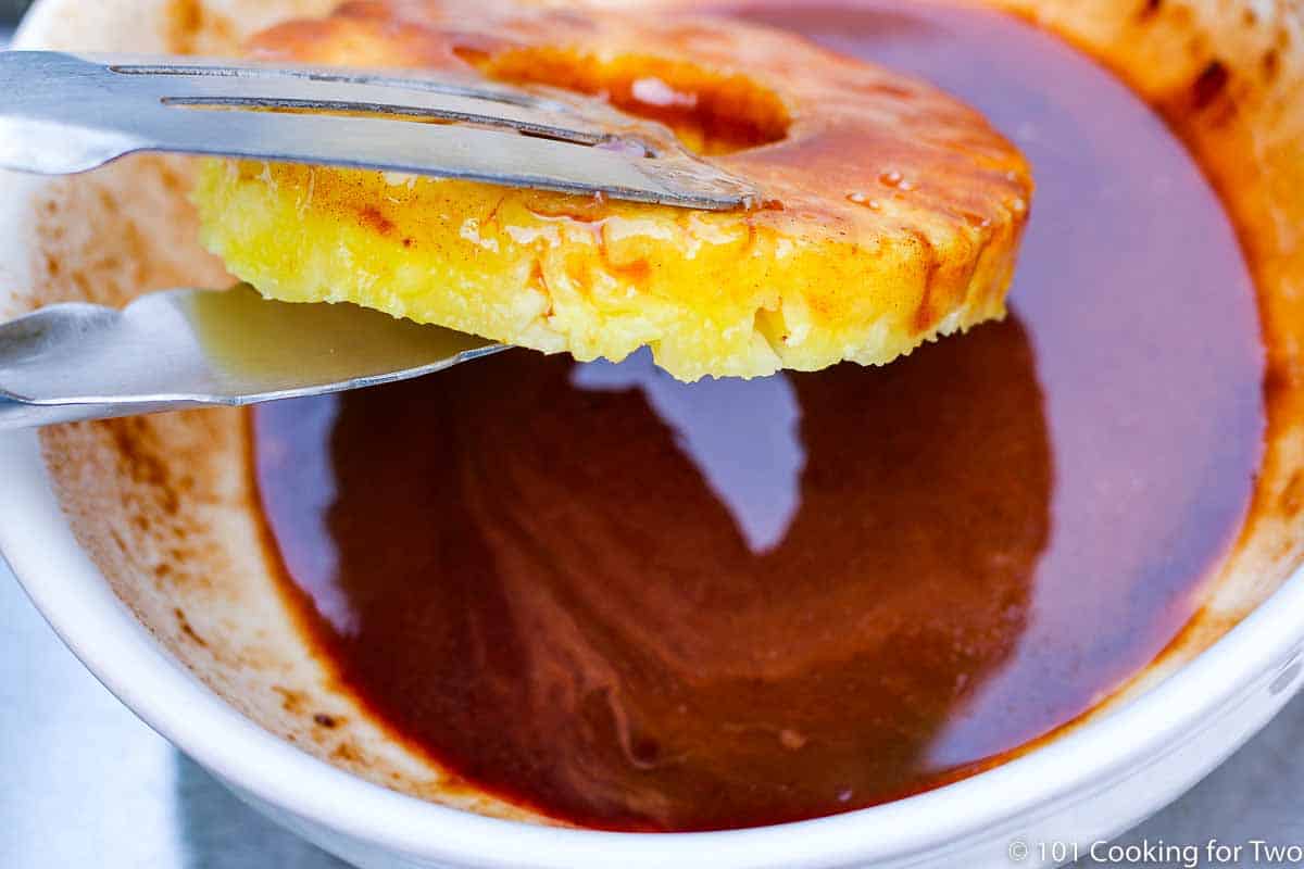 dipping pineapple into the glaze.