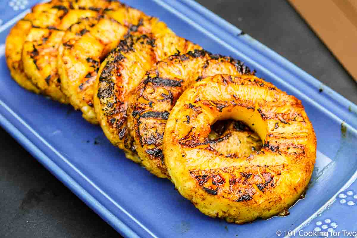 grilled pineapple on blue plate wide view.