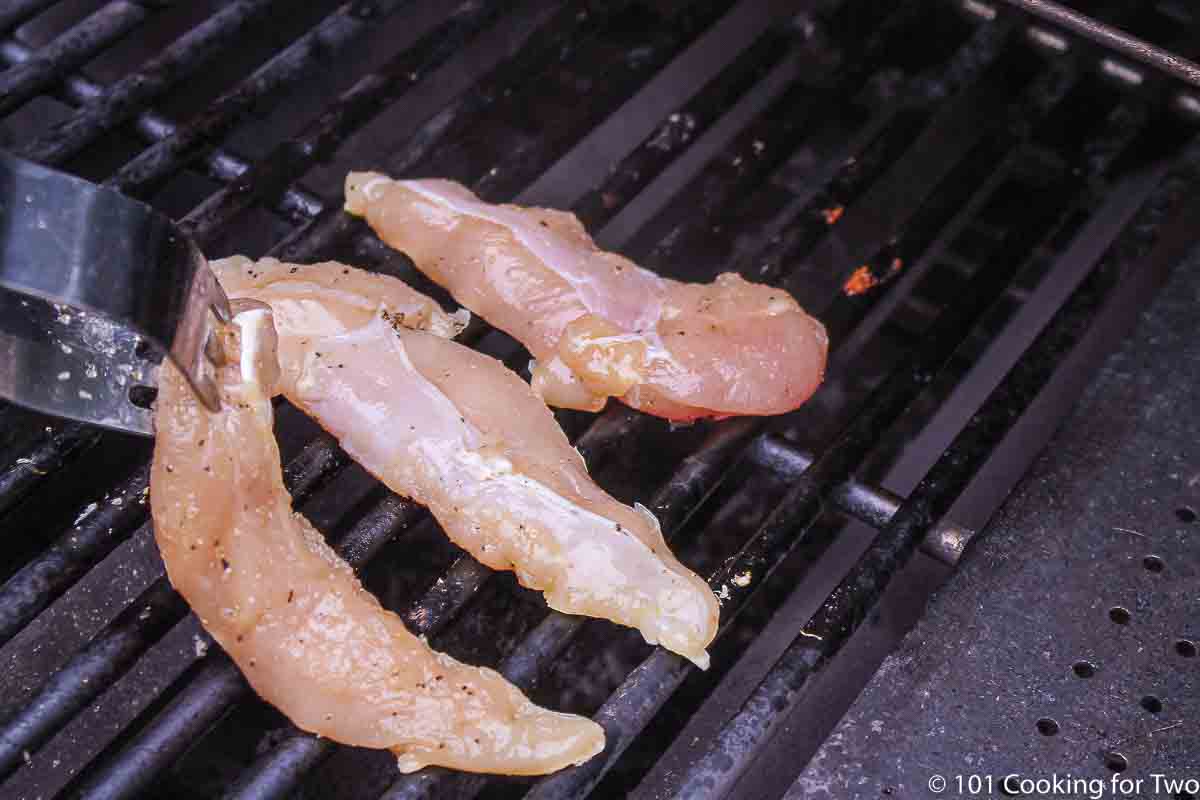 placing chicken tenders on grill grate