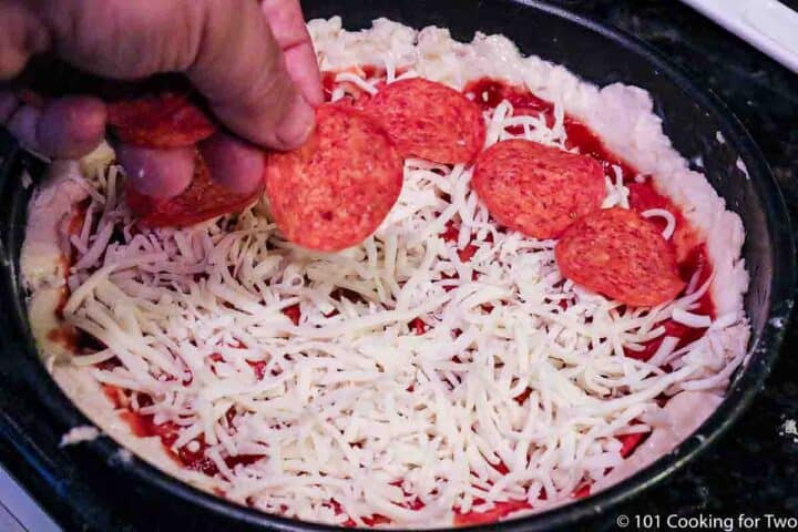 placing toppings on raw pizza