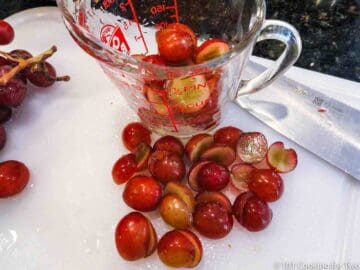 red grapes cut in half a white board