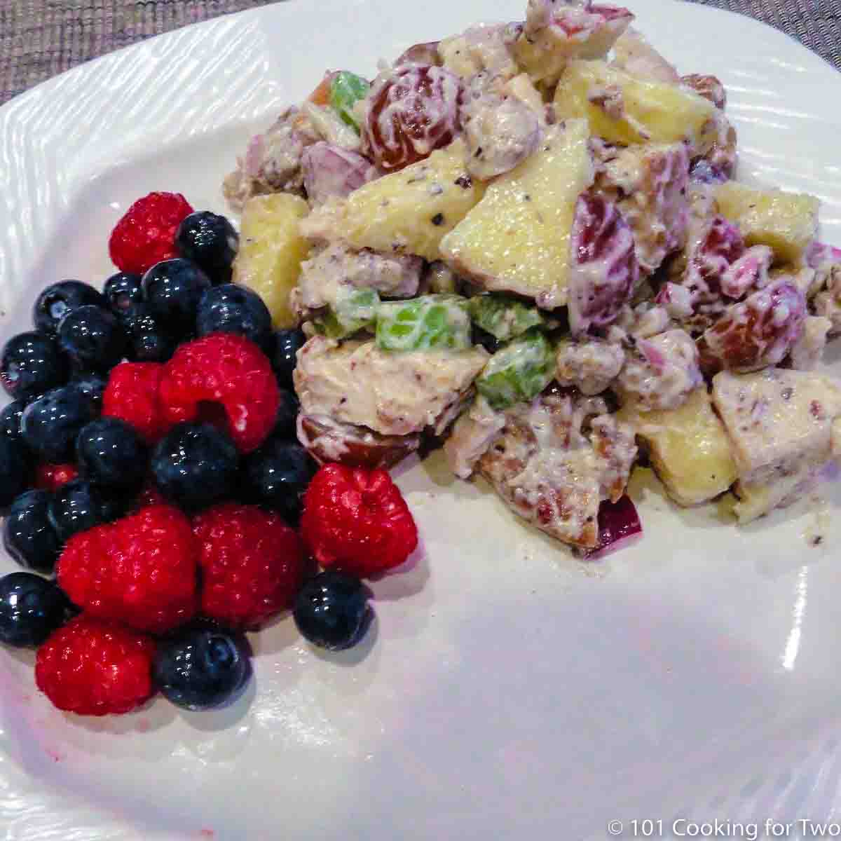 Waldorf chicken salad with fruit on white plate.