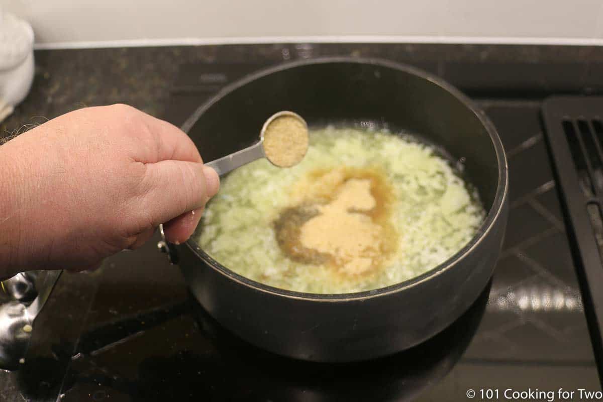 adding seasoning salt to other ingredients in sauce pan