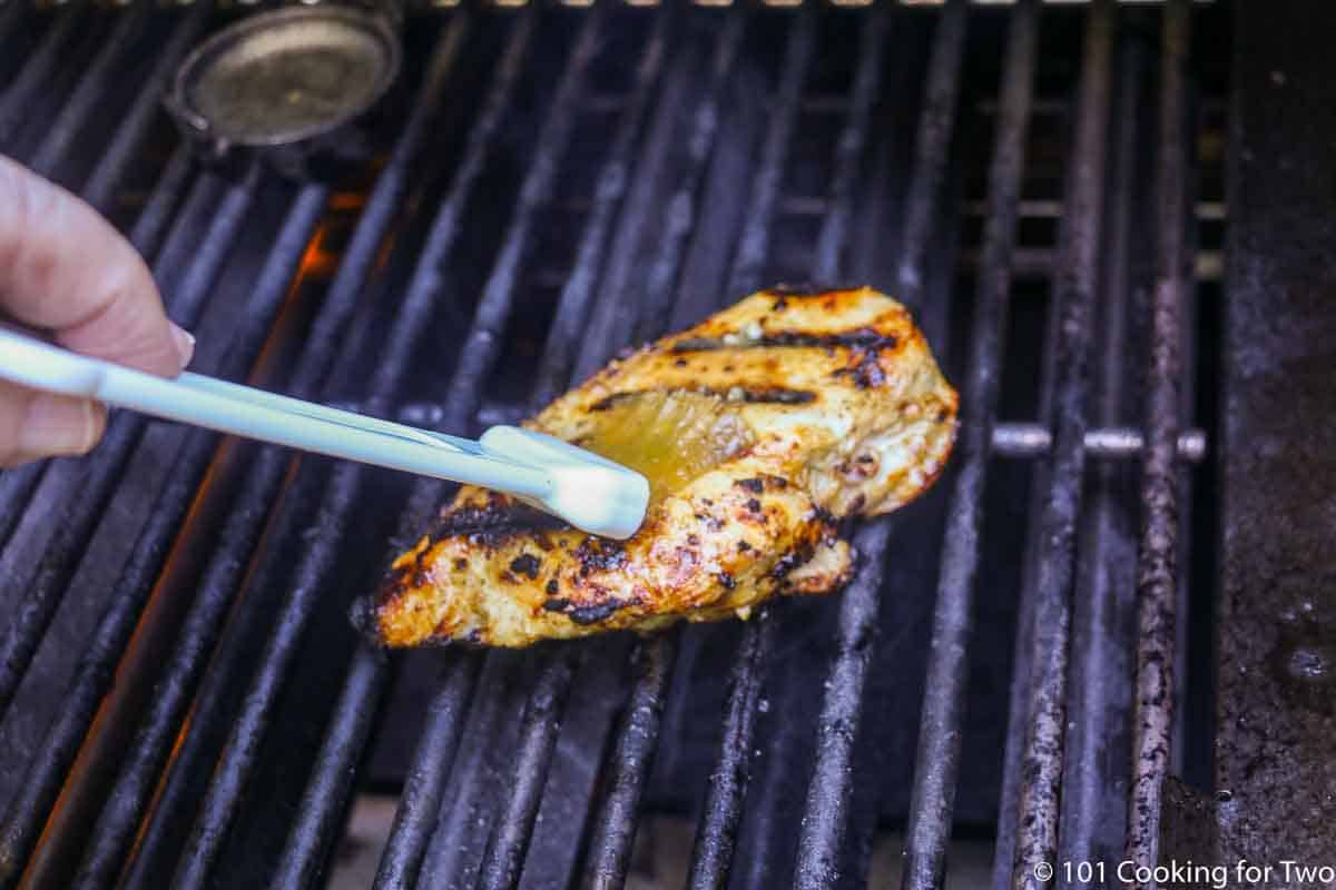 brushing chicken breast with reserved marinade