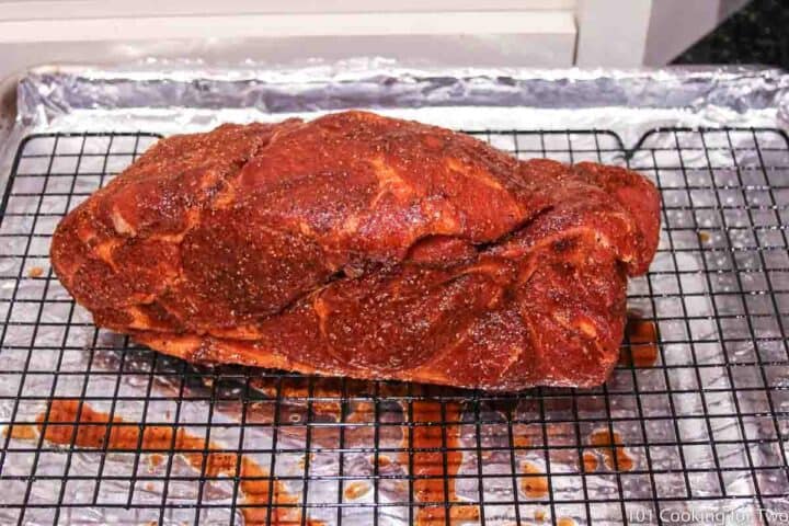 Pork butt with rub on tray with rack