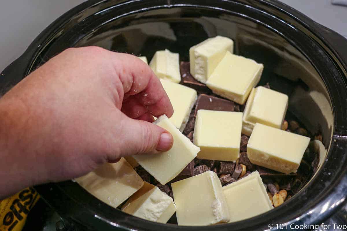 adding peanut cluster ingredients to crock pot.