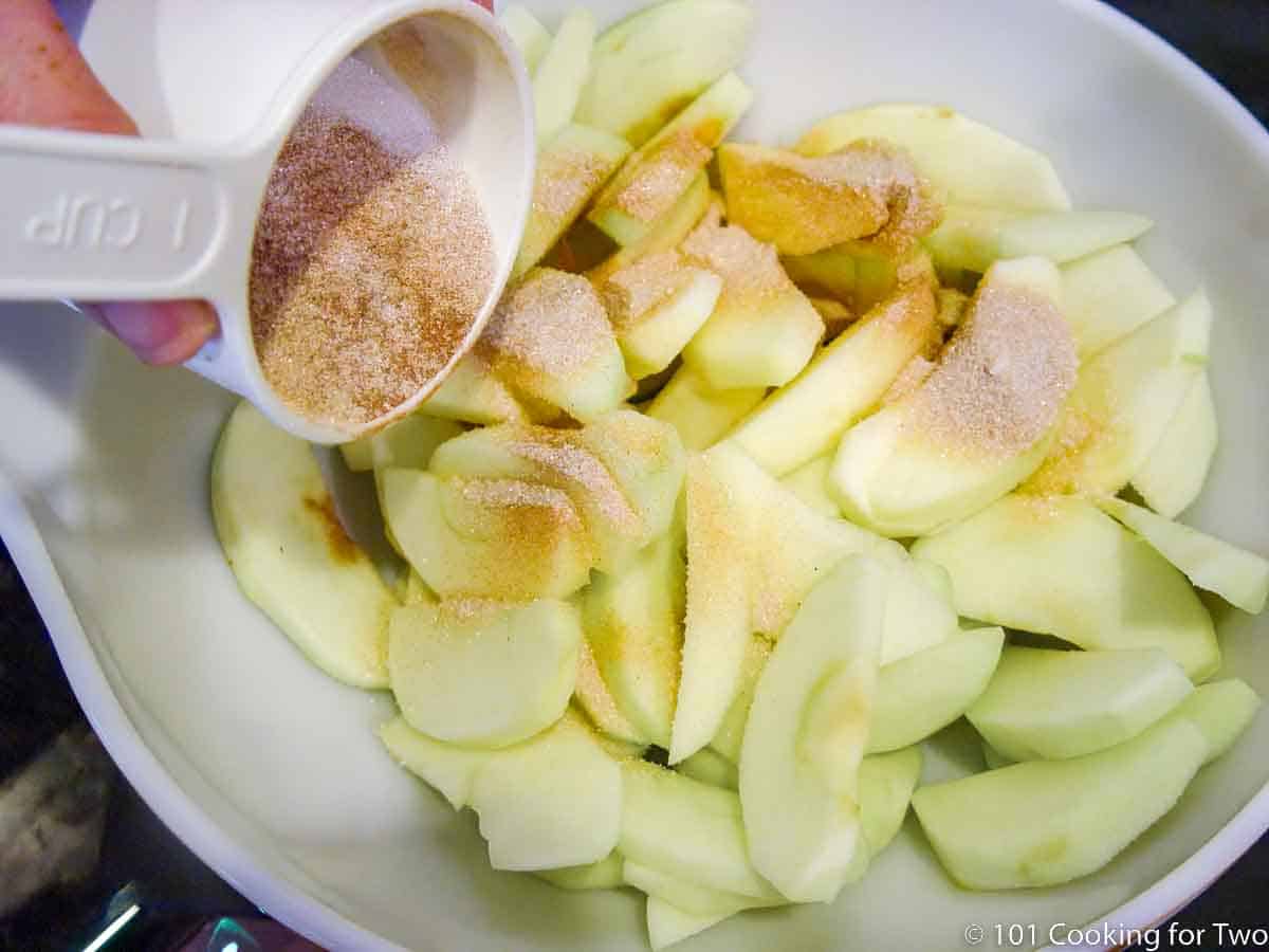 adding sugar and cinnamon to apple slices