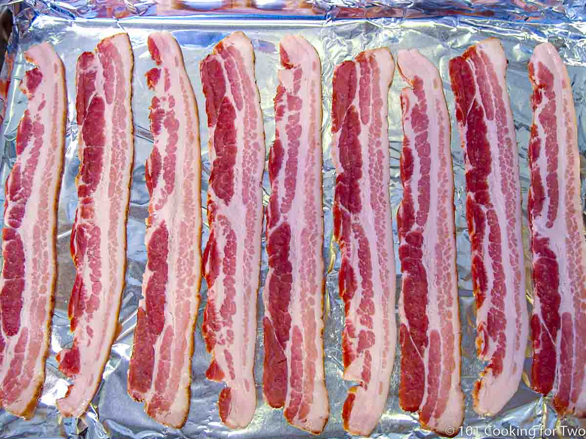 raw bacon on foil covered tray.