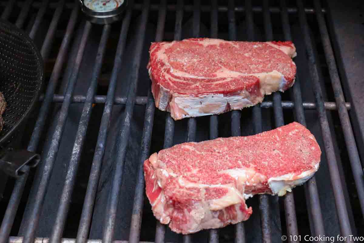 ribeye steaks on grill grate.