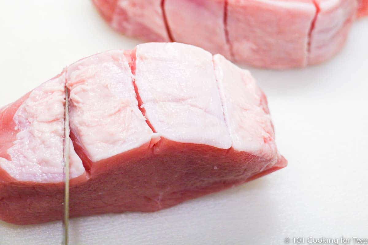 2 inch thick pork chops with trimmed and scored fat.