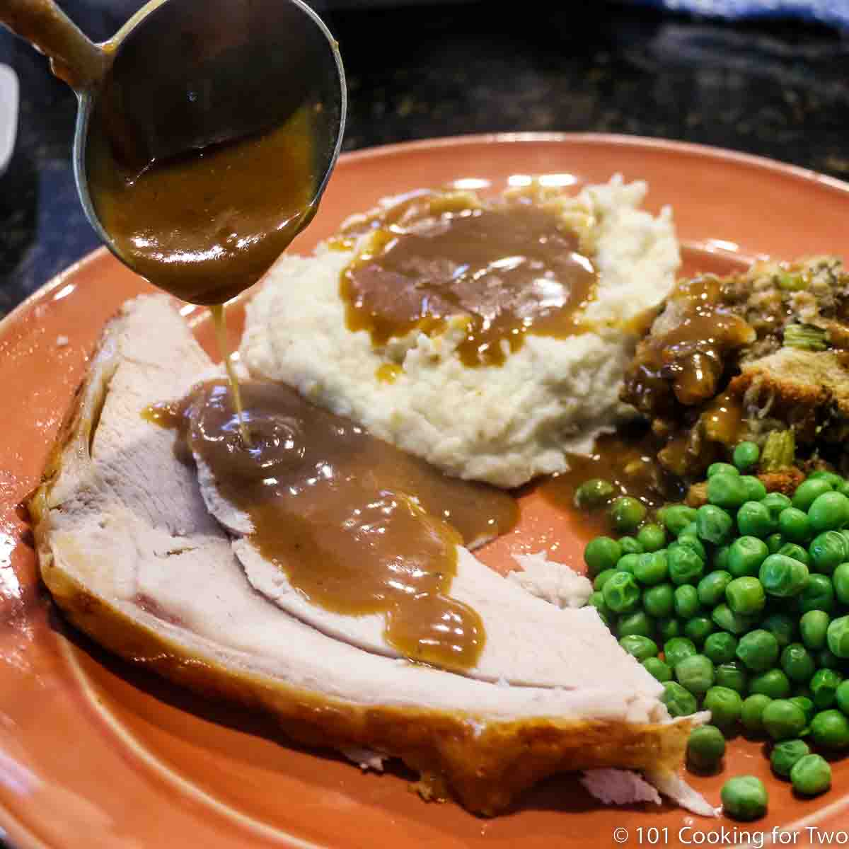 pouring gravy on turkey and potatoes.