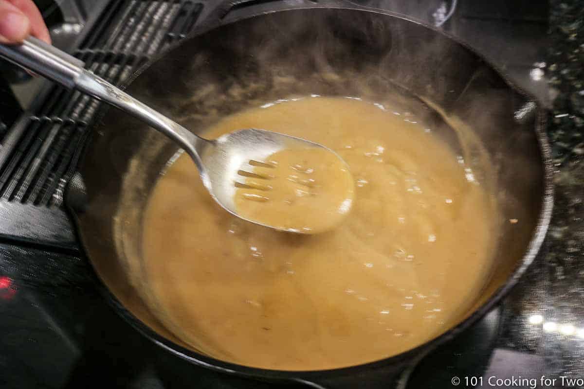 stirring brown gravy in skilling while thickening