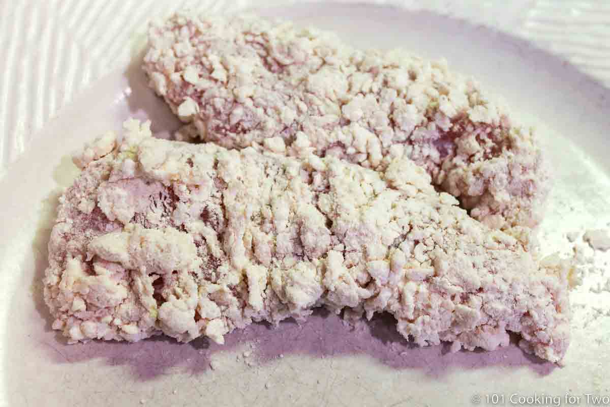 Chicken tenders with shaggy coating on a white plate.