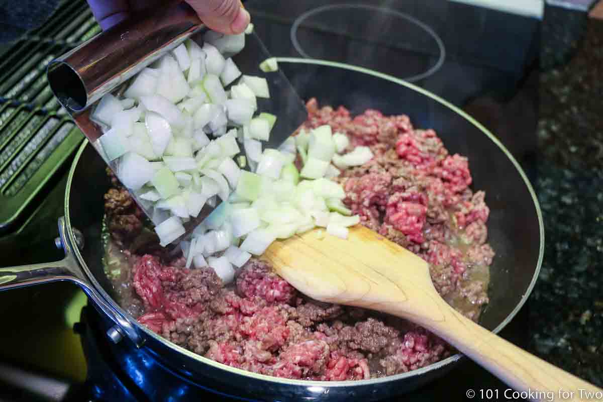 adding chopped onion to browning ground beef.