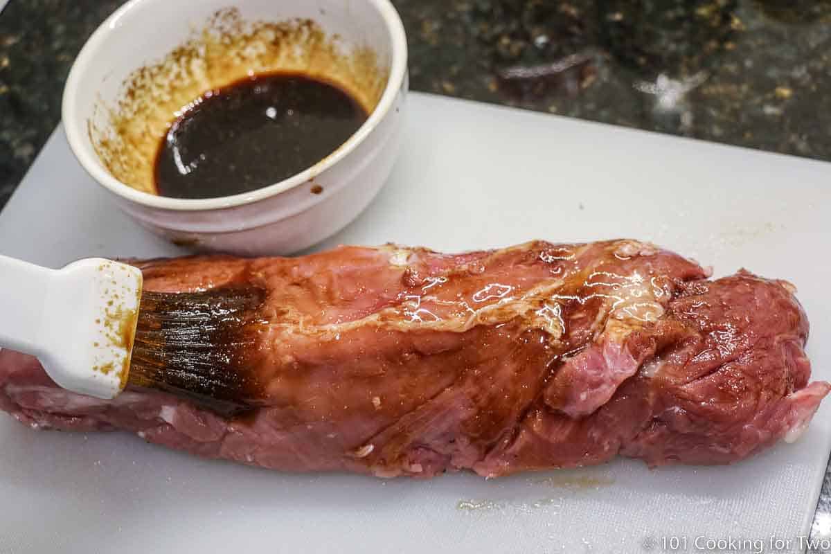 brushing glaze on pork tenderloin.