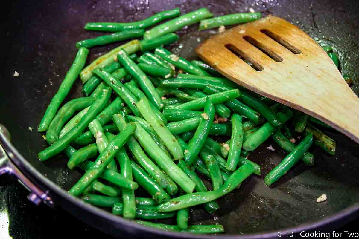 cooking green beans in skillet with garlic.