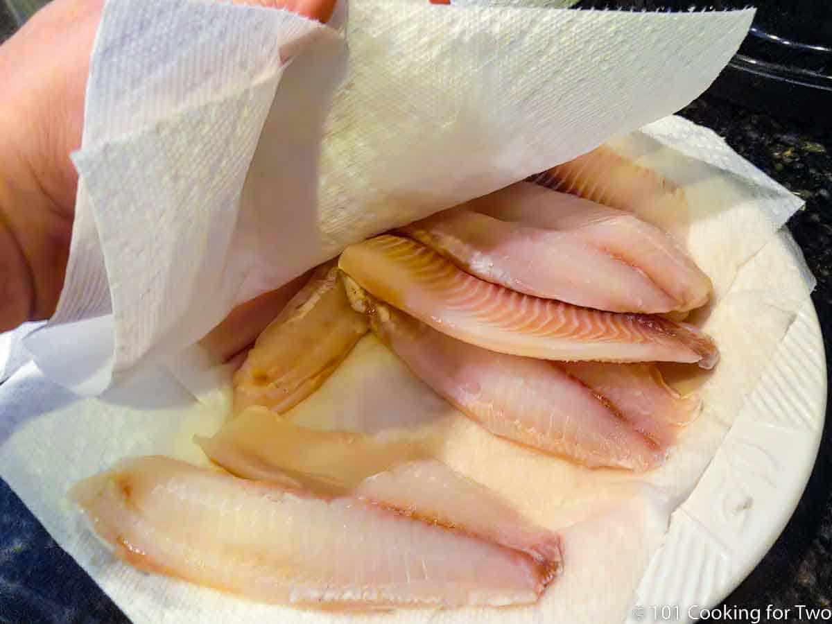 drying tilapia with paper towels.