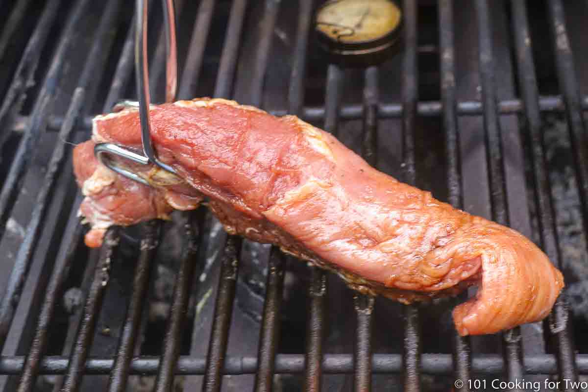 placing pork tenderloin on the grill.