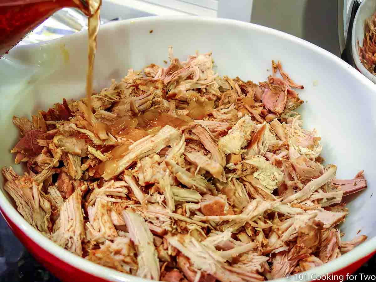 pouring braising fluid into shredded pork loin.