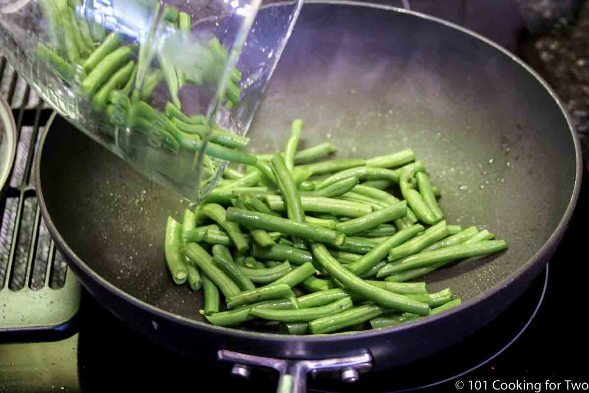 pouring trimmed beans into pan.