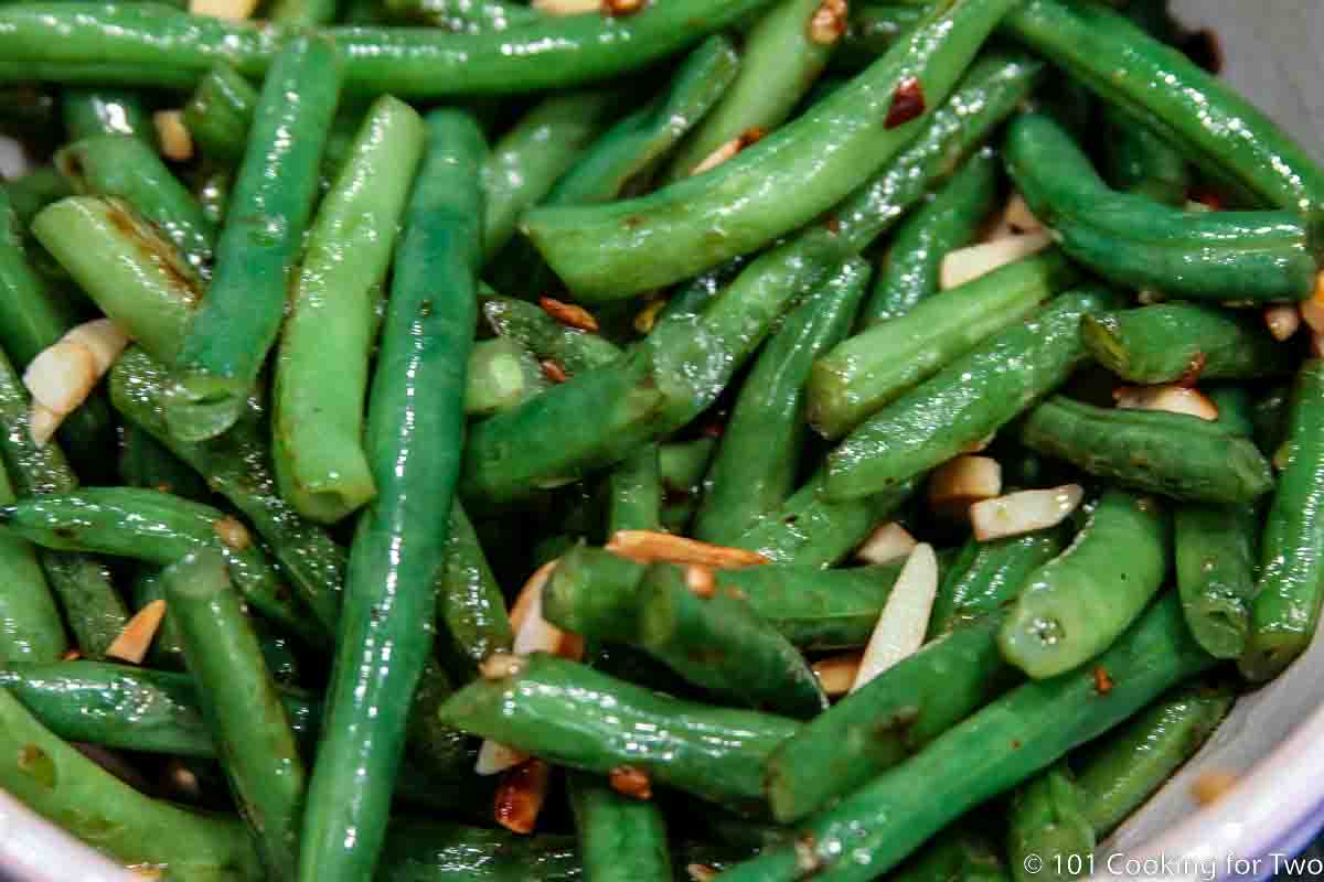 sauteed green beans with almonds in a white bowl.