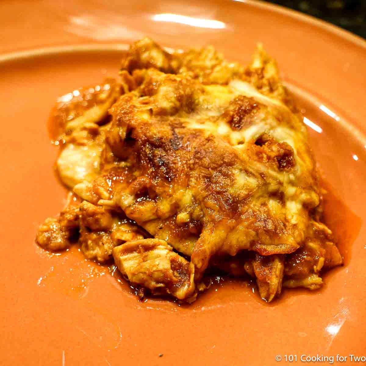 Chicken enchilada casserole on an orange plate.