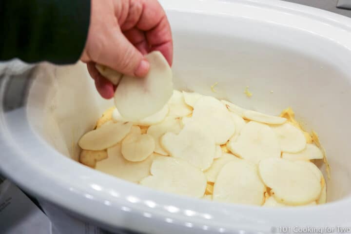 adding slices of potato to crock pot