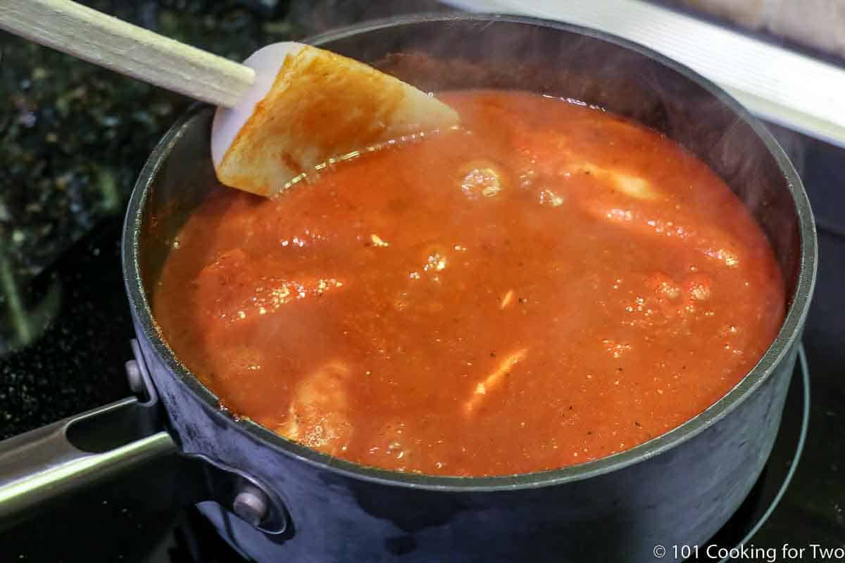 chicken simmering in enchilada sauce.