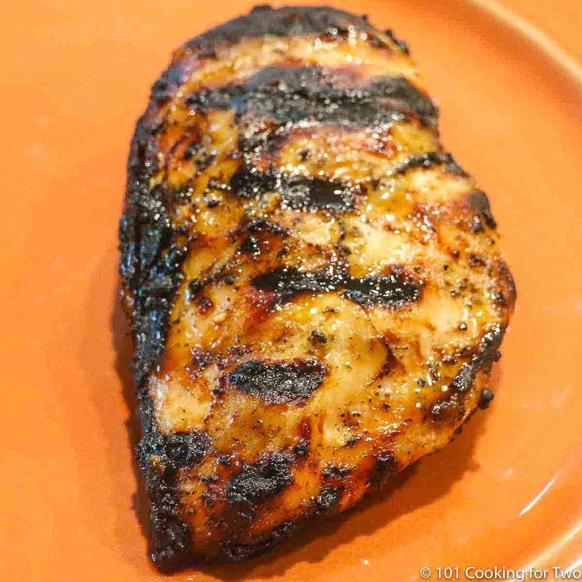grilled chicken breast on an orange plate.
