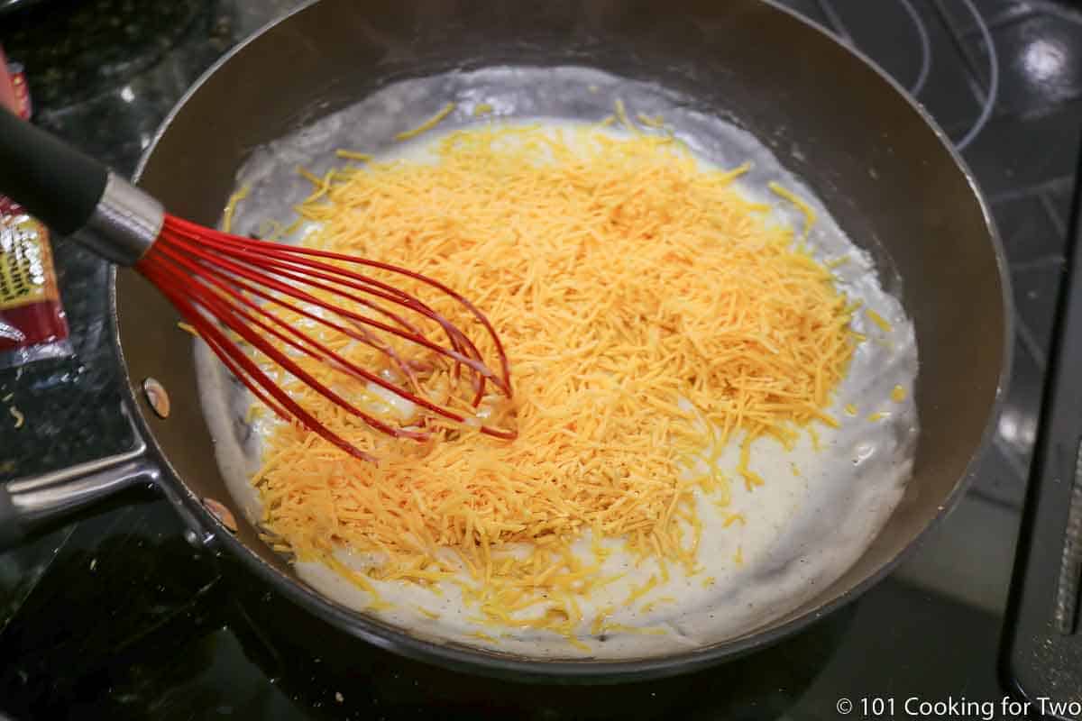 mixing cheese into sauce with a whisk
